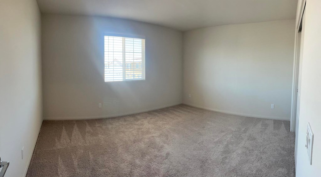 an empty room with a window and carpet