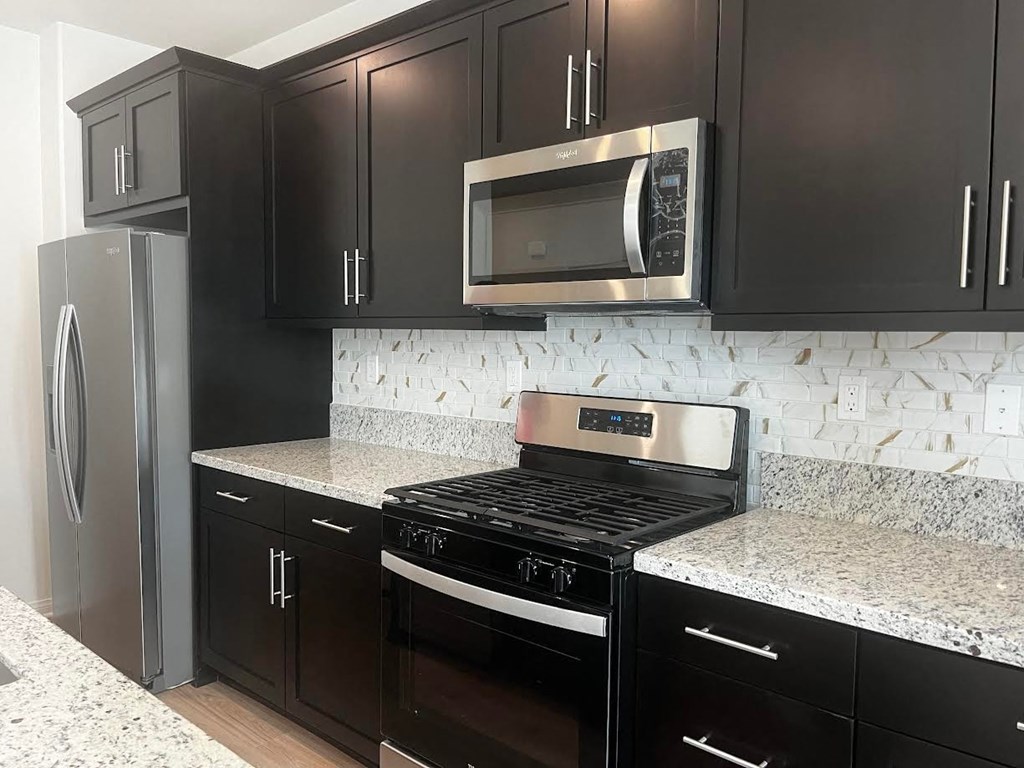 a kitchen with black cabinets and a stove and a microwave