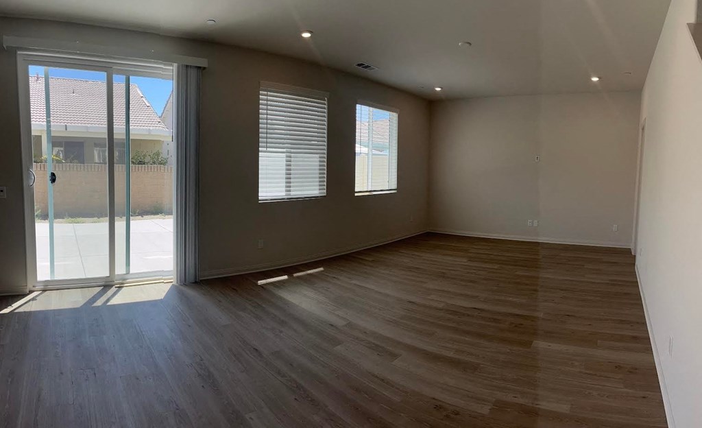 an empty living room with wooden floors and a sliding glass door