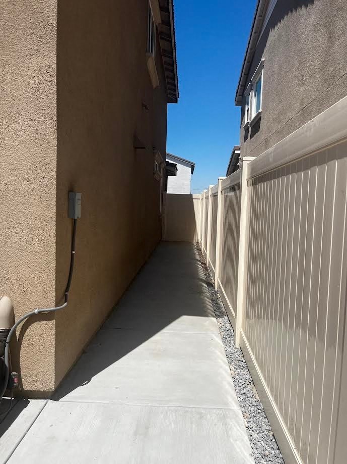a long walkway between two buildings with a white fence