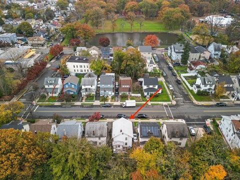 an aerial view of a neighborhood with a red arrow pinpointing a house