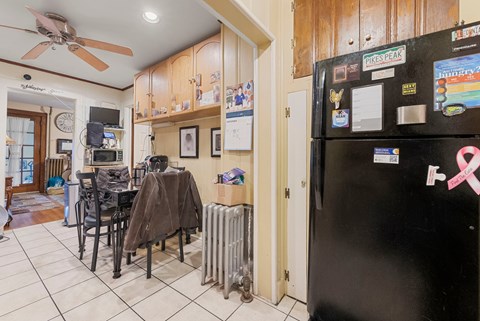 a kitchen with a black refrigerator and a table and chairs