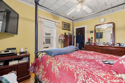 a bedroom with yellow walls and a bed with a red comforter