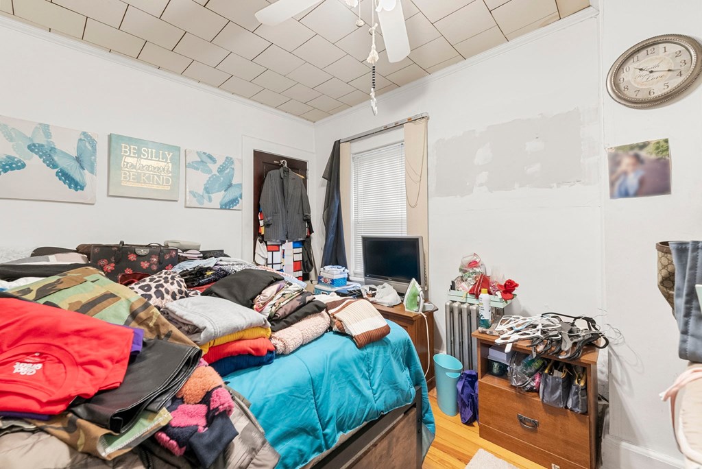 a bedroom with a bed and a dresser with clothes on it