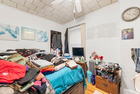 a bedroom with a bed and a dresser with clothes on it