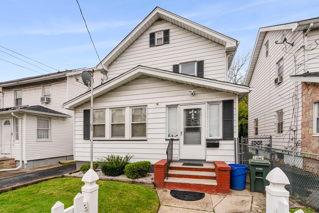 the front of a white house with a front yard