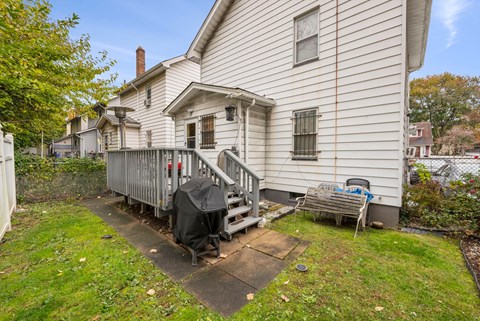 the back of a white house with a deck and a wooden fence