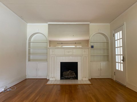 a living room with white walls and a fireplace and wooden floors