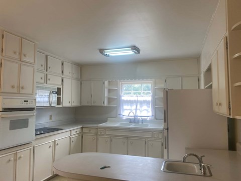 a kitchen with white cabinets and a sink and a window