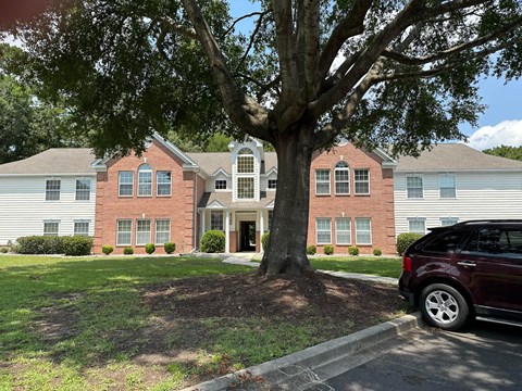 A red brick house with a tree in front.
