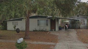 A house with a white fence and a tree in front.