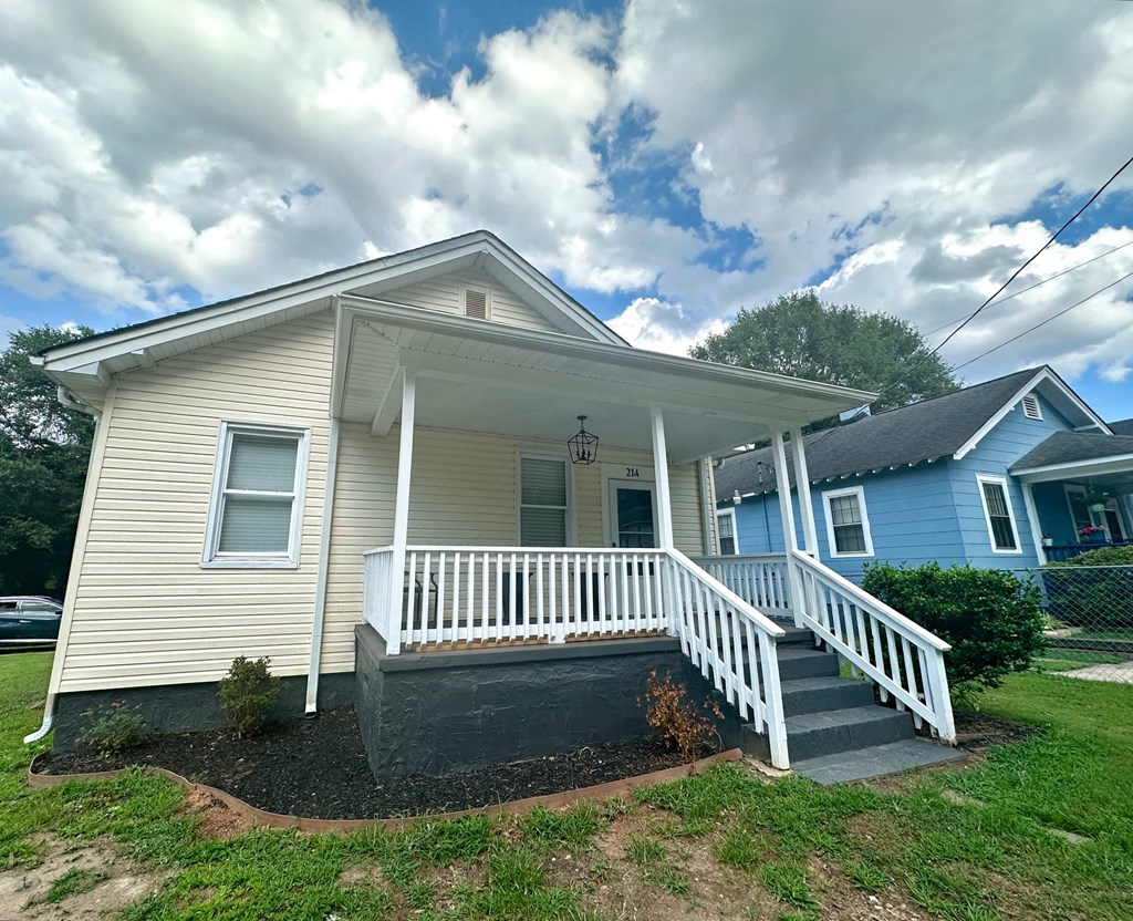 a white house with a porch and a blue house next to it