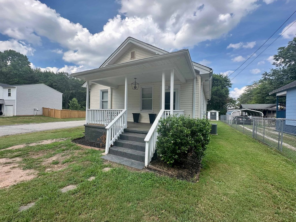 a small white house with a front porch and a grassy yard
