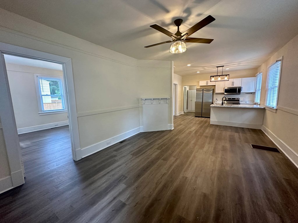 an empty living room and kitchen with a ceiling fan