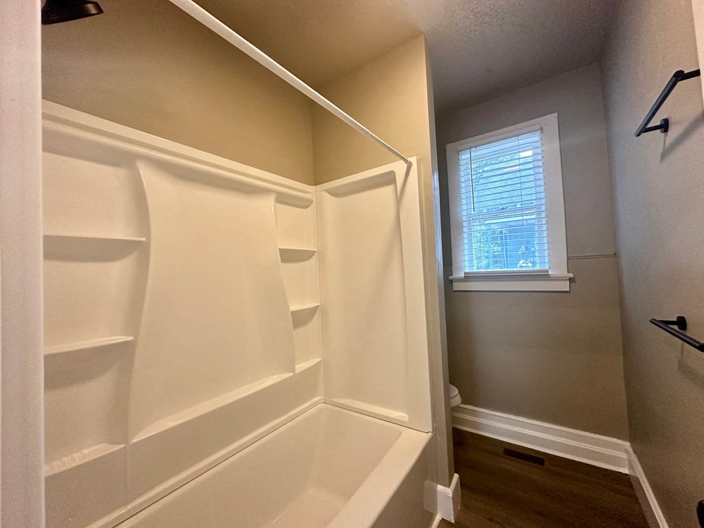 a walk in closet with white shelves and a window