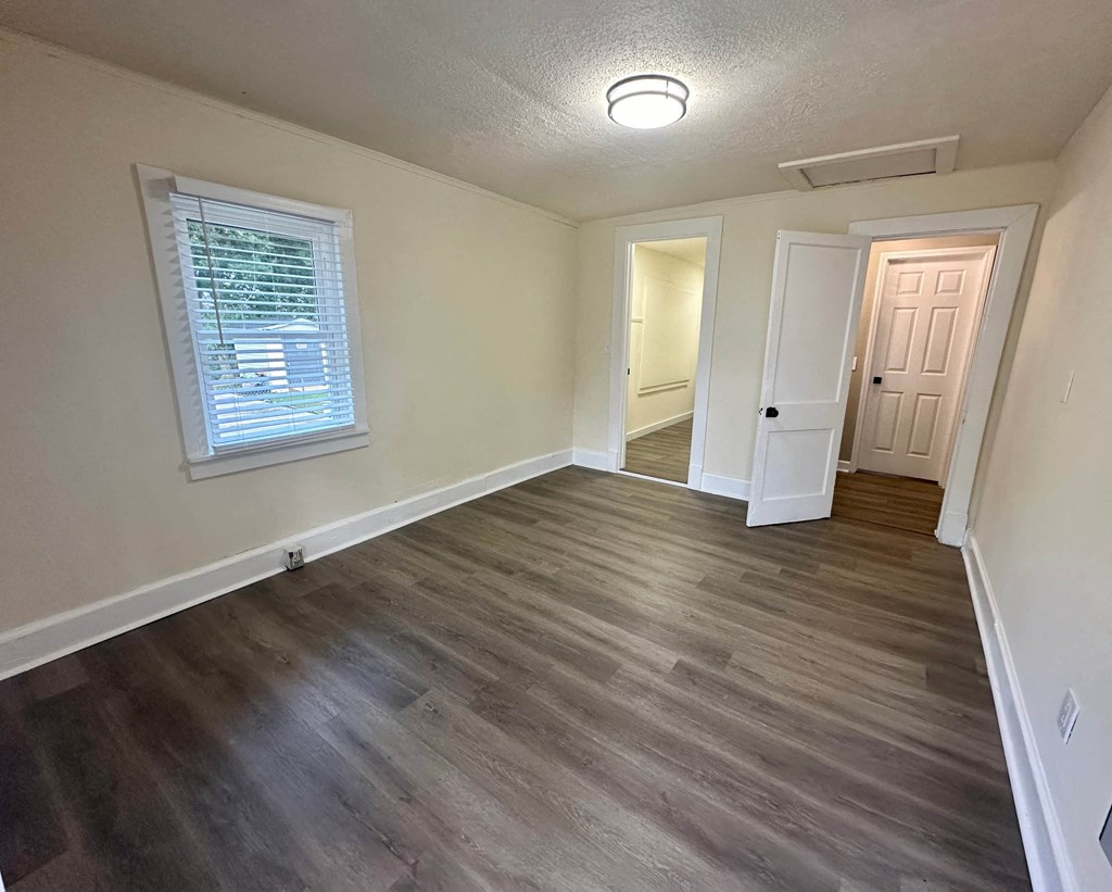 an empty living room with hardwood floors and a window