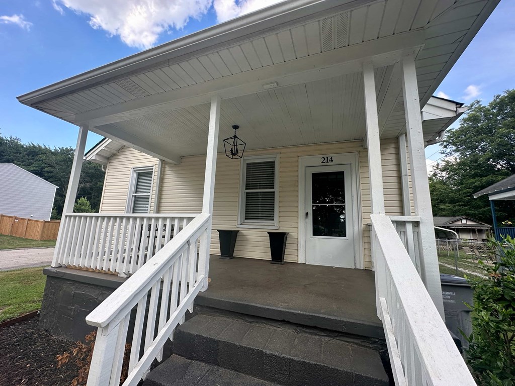 the front of a house with a porch and a white door