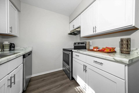 A kitchen with white cabinets and a marble countertop.