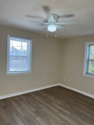 an empty room with a ceiling fan and two windows
