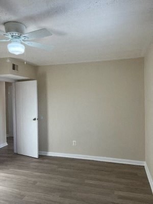 an empty living room with a ceiling fan and a door