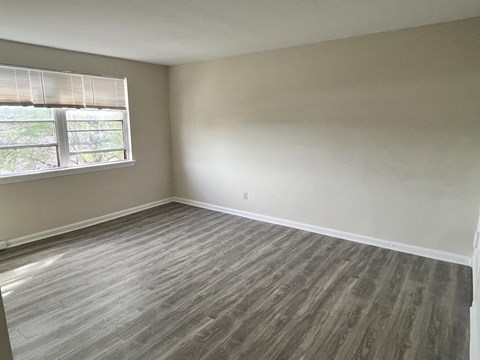 an empty bedroom with wood floors and a window