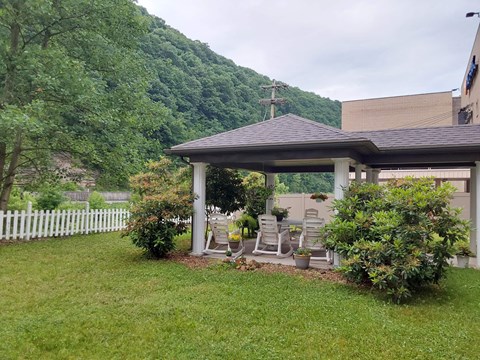 a covered patio with a white fence and a house