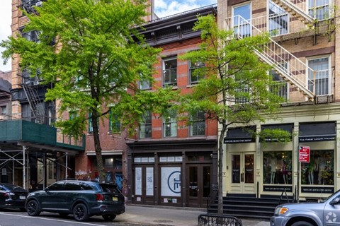 A black SUV is parked on the street in front of a building with a white sign that says "T".