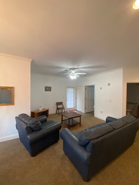 Two blue couches in a living room with a ceiling fan.