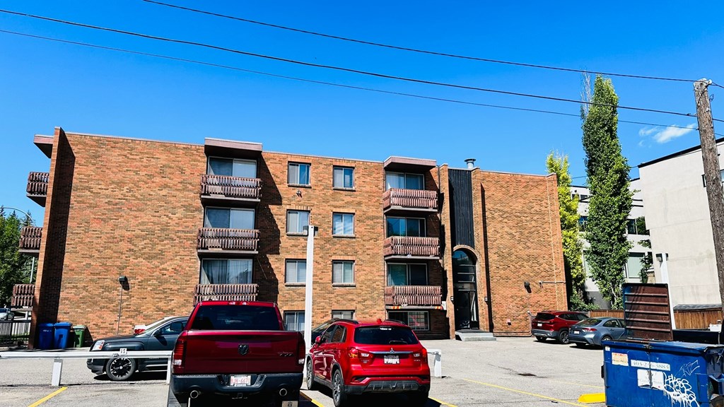 A red truck is parked in front of a red car.