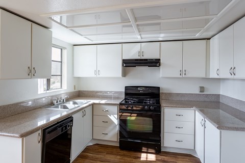 A kitchen with white cabinets and a black stove top oven.