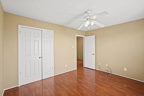 an empty living room with wood floors and a ceiling fan