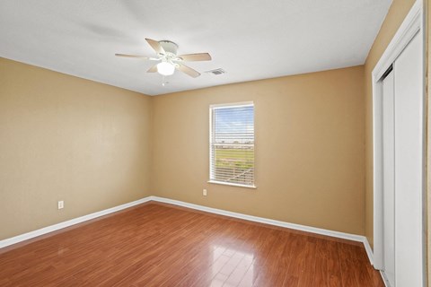 an empty living room with wood floors and a ceiling fan