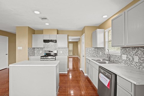 an empty kitchen with white cabinets and a counter top