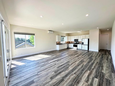 A spacious room with wooden flooring and a large window.