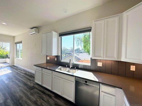 A modern kitchen with white cabinets and a dark countertop.