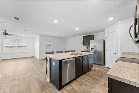 a kitchen with an island and a stainless steel refrigerator