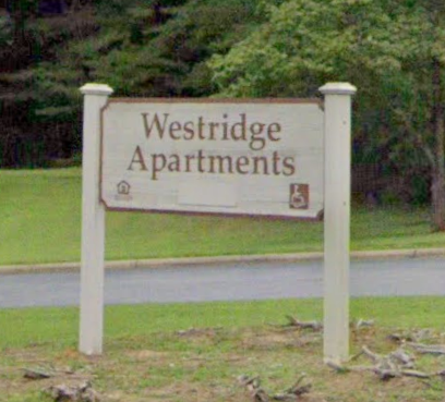 a sign for the apartments on the side of the road