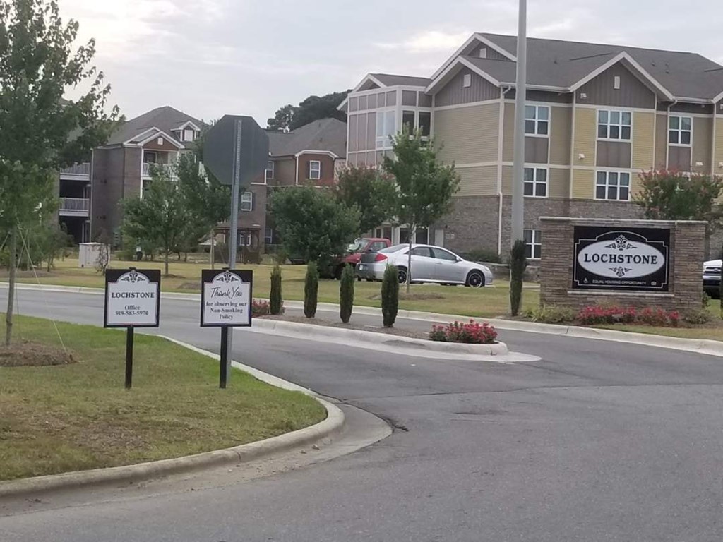 an empty street with signs in front of an apartment building
