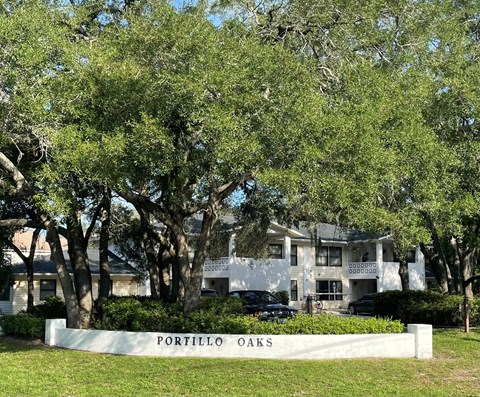 a sign in front of an apartment building with trees