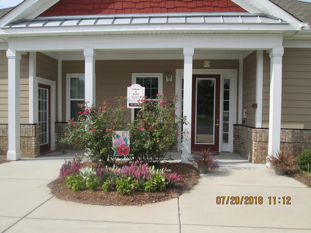 a front porch with flowers and a sign in front of a house