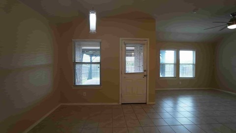 an empty living room with a white door and windows