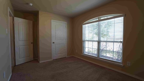 an empty bedroom with a large window and a door