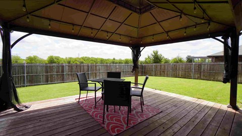 a gazebo with a table and chairs on a deck