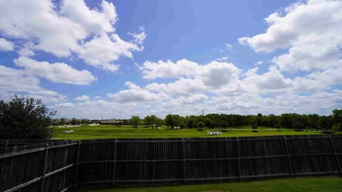 a view of the golf course from behind a fence