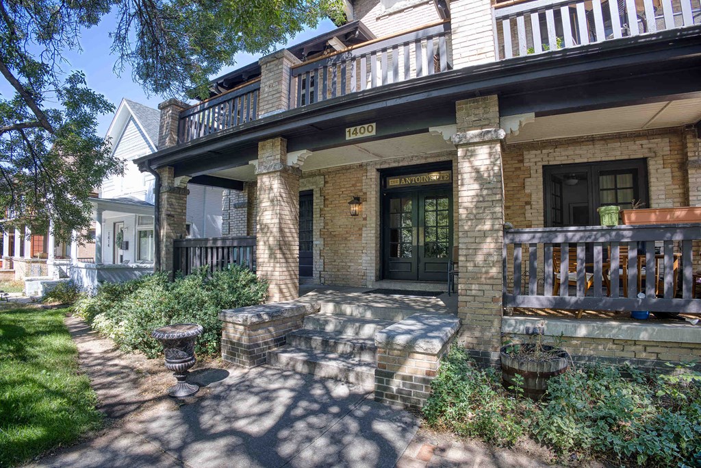 the front of a brick house with a porch and a balcony
