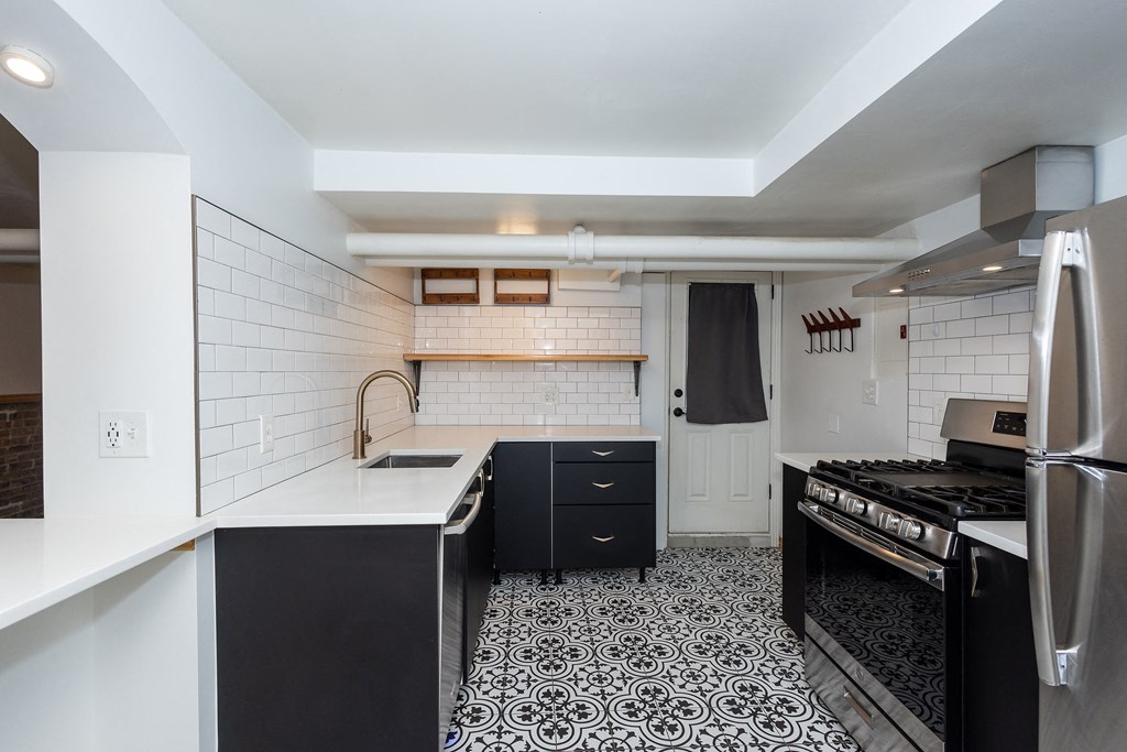 a kitchen with black and white tiles and a stove and a sink