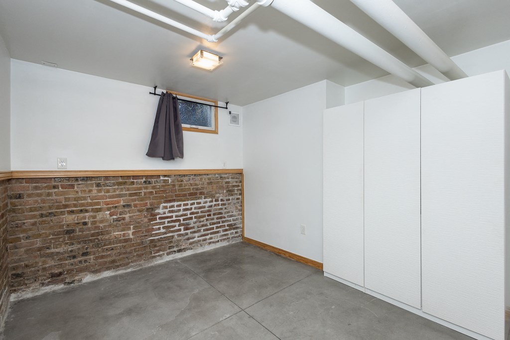 an empty room with white cabinets and a brick wall
