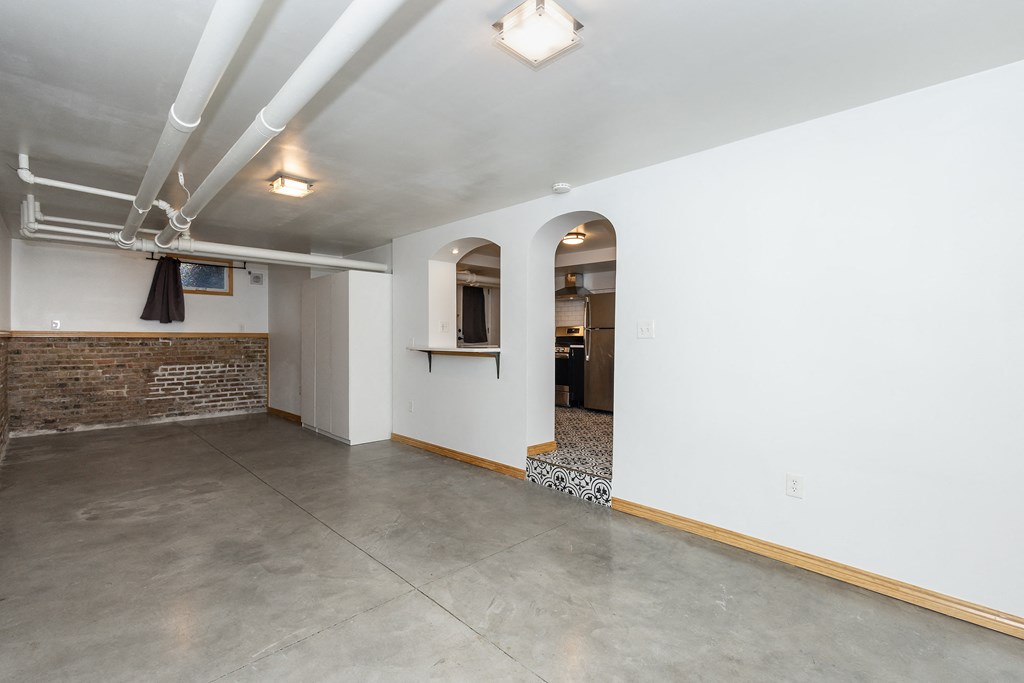 a living room with white walls and a concrete floor and an arched doorway
