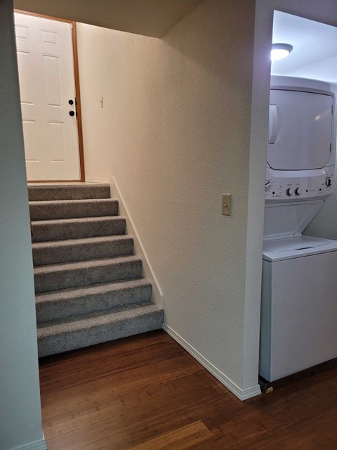 a stairway leading up to a bathroom with a washing machine and a dryer