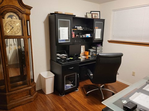 an office with a desk and a grandfather clock
